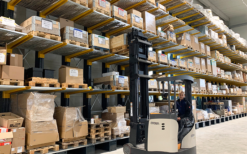 Alois Müller Group warehouse. Forklift operator in the foreground of shelves